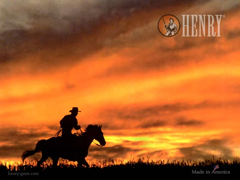 Silhouetted cowboy riding horse against dramatic sunset sky