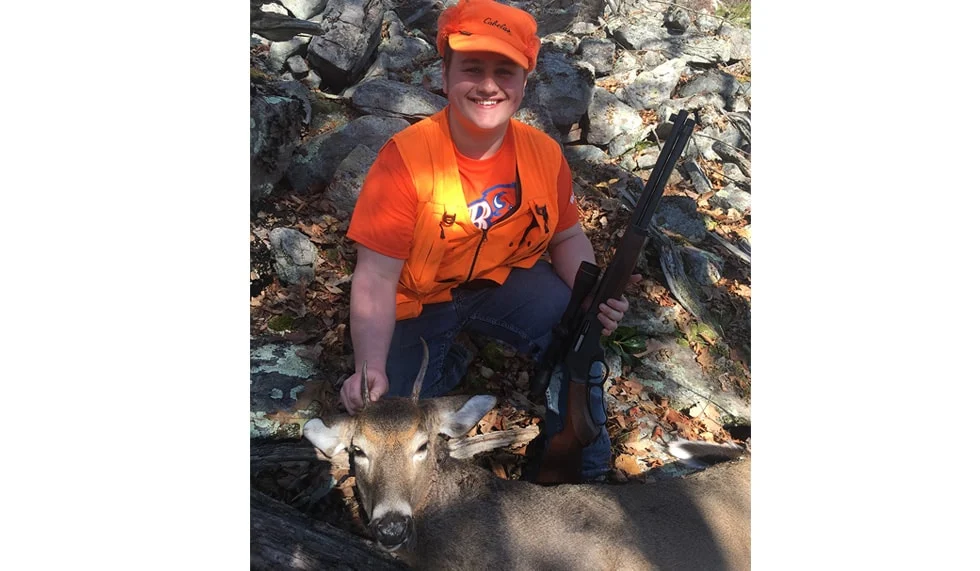 Hunter in orange vest holding a deer after a successful hunt