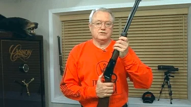 Man in orange shirt demonstrating lever-action rifle maintenance techniques for Henry Repeating Arms firearms