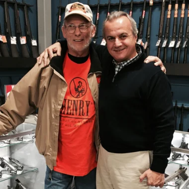 Two men shaking hands in gun shop, representing the Henry Repeating Arms company leadership