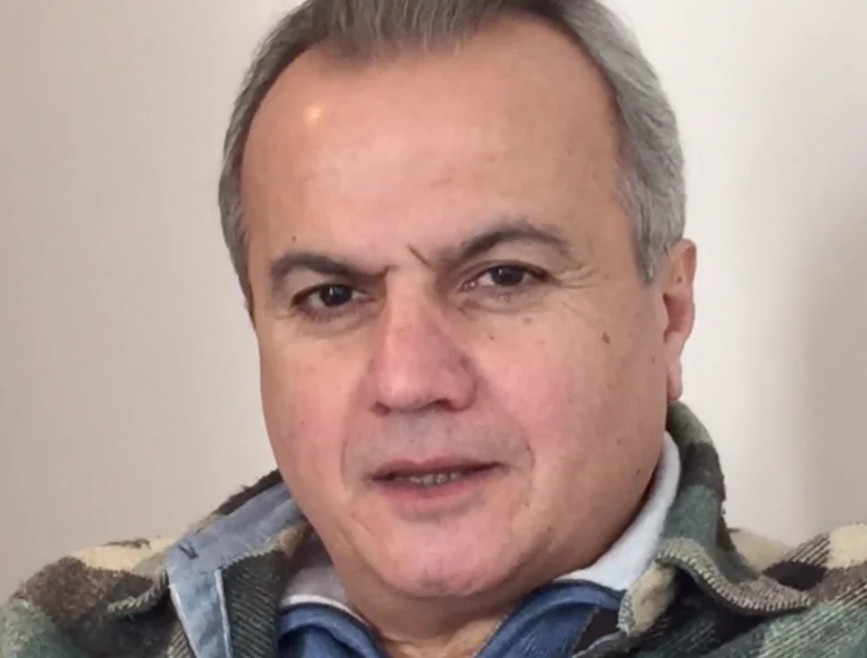 Portrait of a man with grey hair wearing a plaid jacket