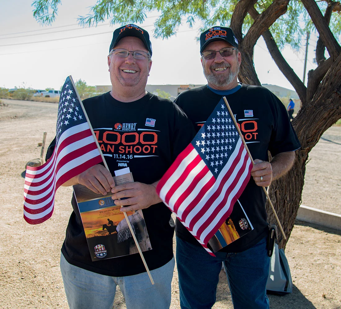 Two men celebrating the 1,000 Man Shoot anniversary with American flags and Henry Repeating Arms gear