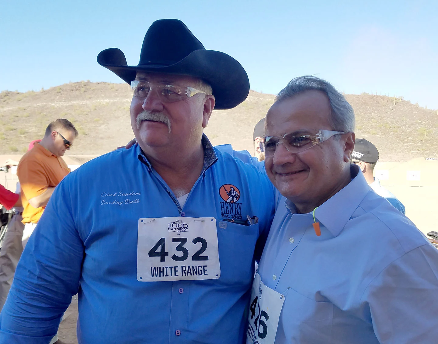 Two men wearing cowboy hats and shooting attire standing at the Henry Repeating Arms shooting event