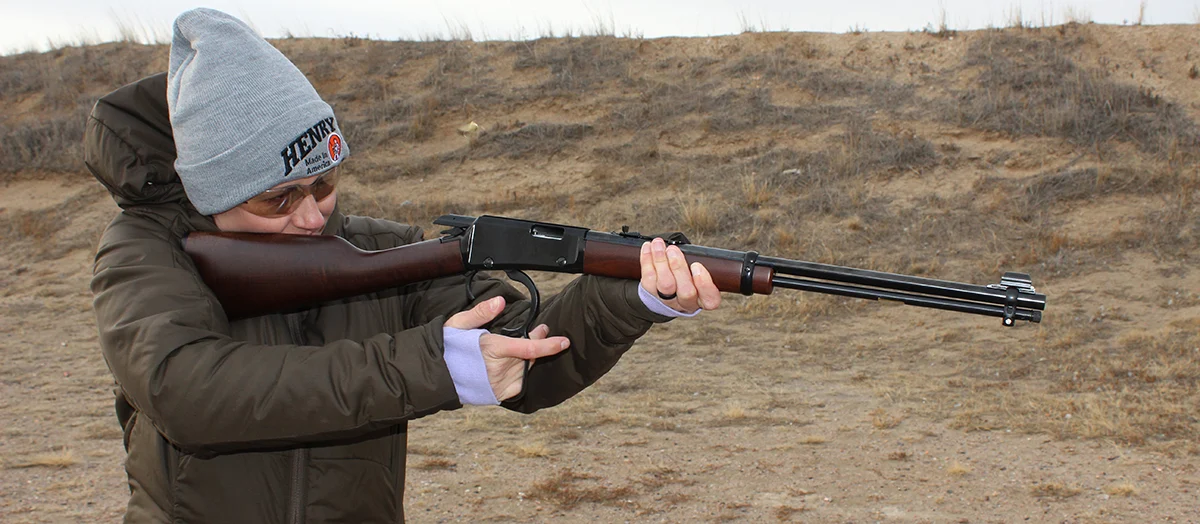 Man aiming lever-action rifle in outdoor shooting range