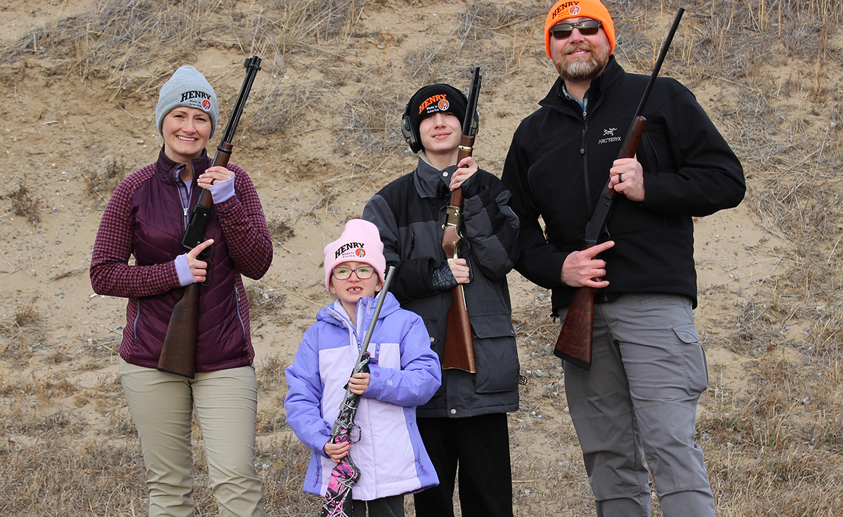 A multi-generational family standing outdoors with their firearms, passing down the legacy of responsible gun ownership