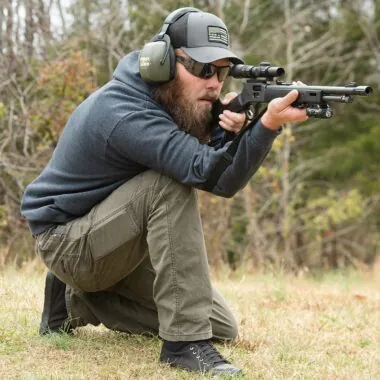 Man aiming a Henry X Model from a kneeling position