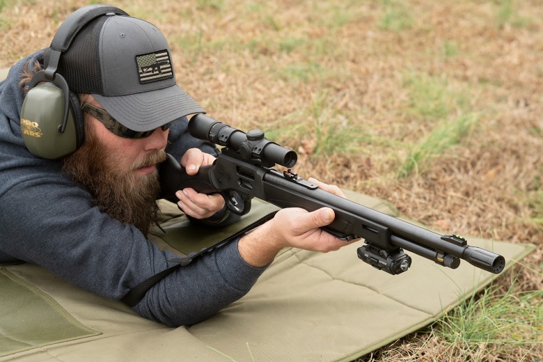 Man aiming a Henry X Model rifle from a prone position