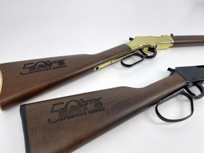 Wood buttstocks on two different rifles showing engraved 50th anniversary logos