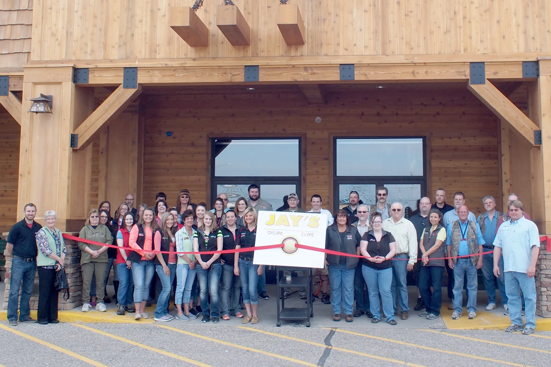 Group of around 20 employees standing in front of a new store location in preparation for a ribbon cutting ceremony