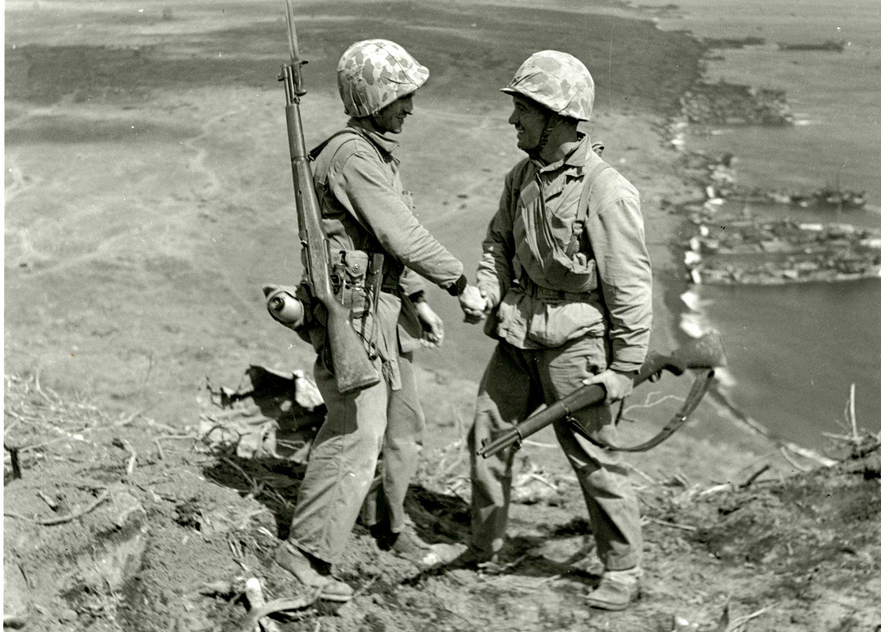 Two WW2 soldiers in combat gear on rugged terrain