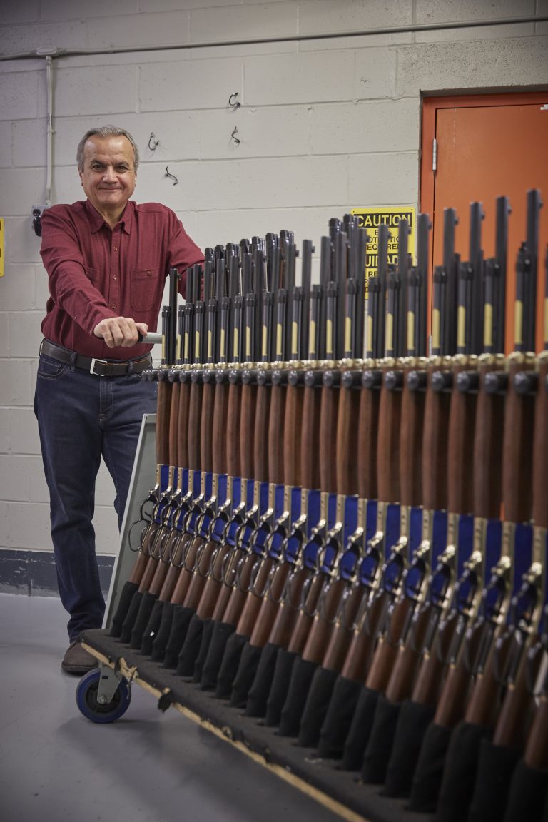 Anthony Imperato with a rack of completed Henry .45-70 lever action rifles awaiting final inspection and packaging.