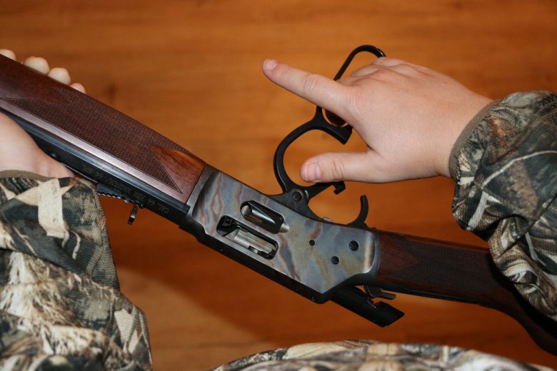 Hand opening the action of a rifle