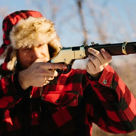 Person in red winter clothing aiming rifle outdoors