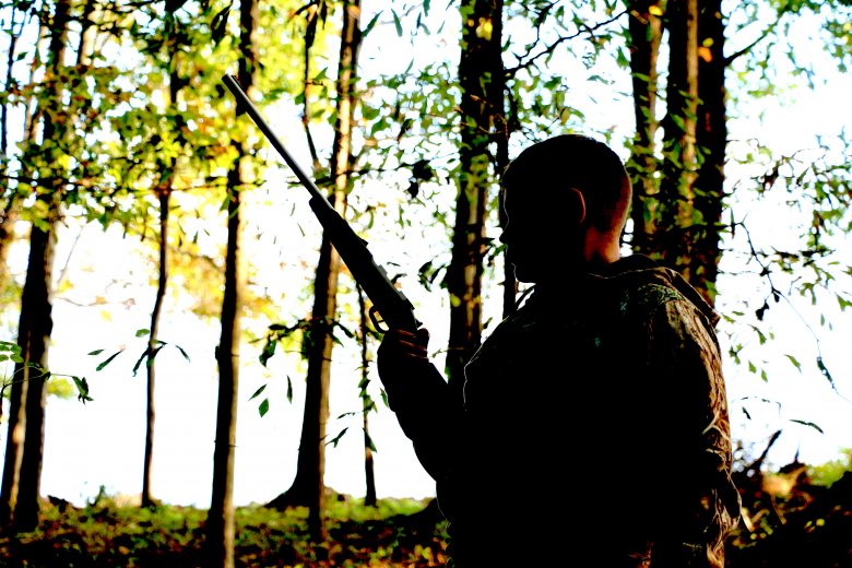 Young hunter holding a rifle in the woods