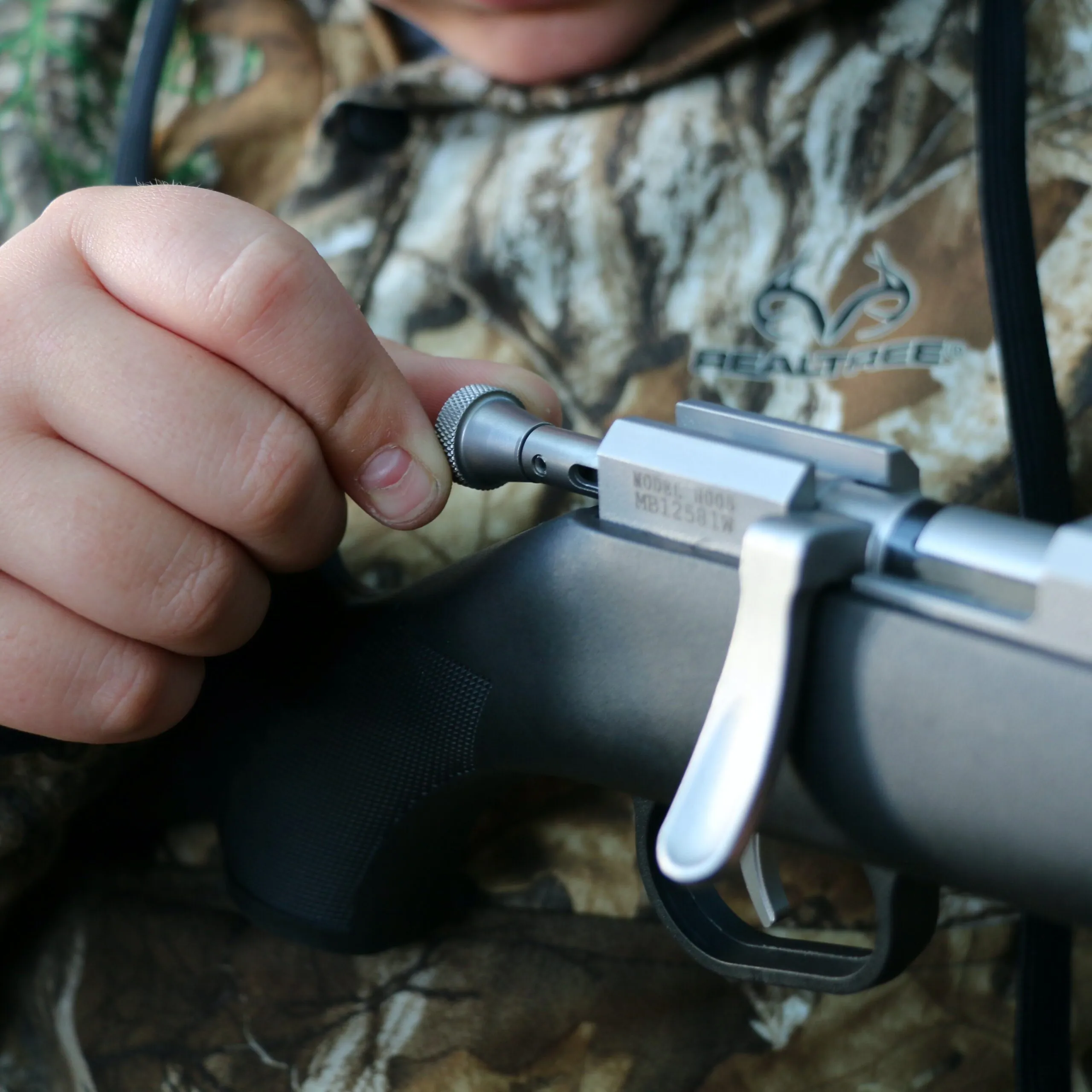 Young hunter pulling back the safety on a youth bolt action rifle