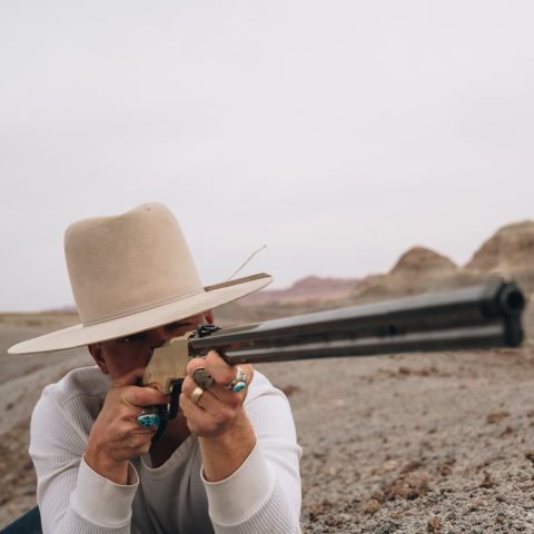 Man with a Stetson hat aiming a Henry rifle