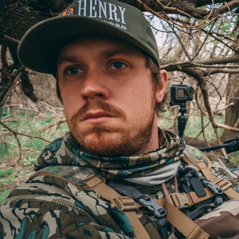 Photograph of a hunter in camo clothing looking out from a blind
