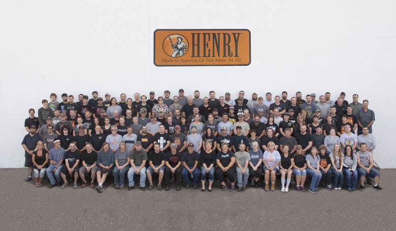 Large group of Henry employees posing for group photo in front of building.