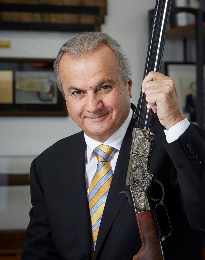 Anthony Imperato holding up a silver engraved rifle.