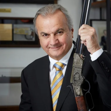 Man in suit holding up an ornately engraved Henry lever-action rifle