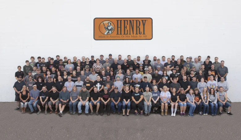Large group photo of employees posing in front of Henry Repeating Arms facility