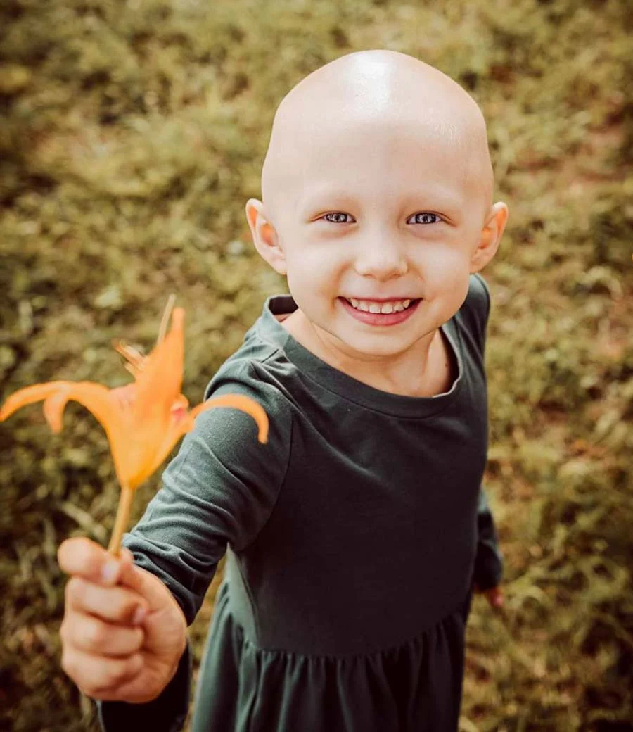 Smiling child holding nature-themed accessory in outdoor setting for Henry Repeating Arms charitable campaign