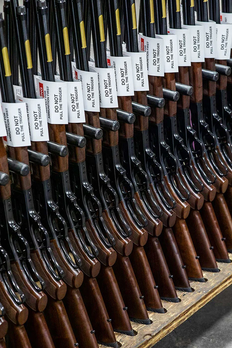 Rows of Henry Repeating Arms rifles in the company's factory, showcasing their domestic manufacturing.