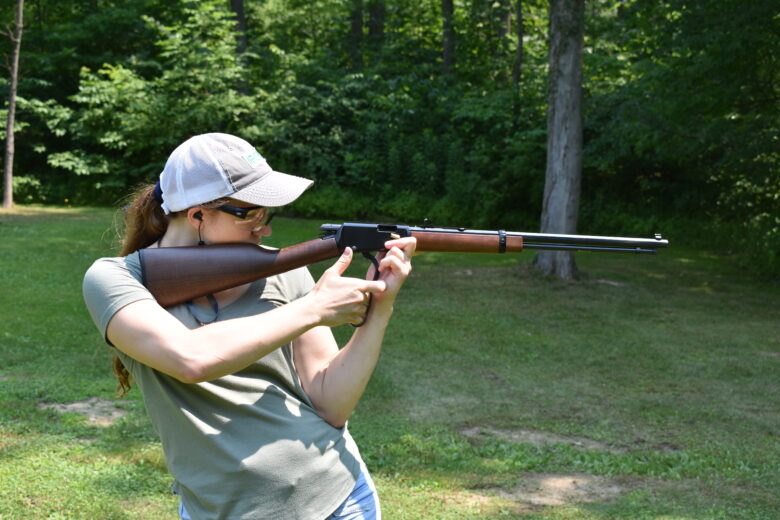 Profile view of the author working the lever of a rifle shooting in an offhand position.