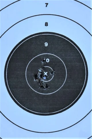 A paper target with several shot holes, demonstrating accurate firearm handling and marksmanship.