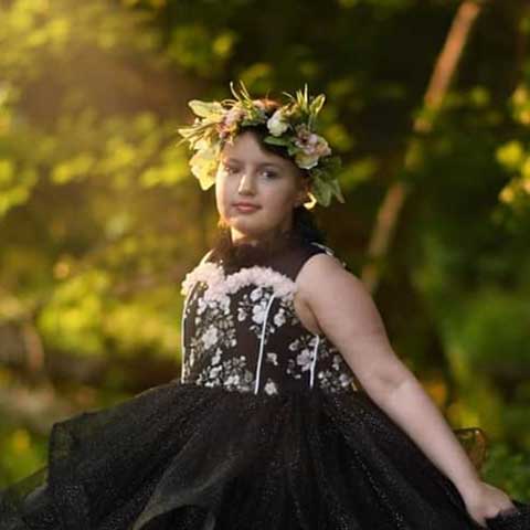A young girl with her family members posing in front of a memorial wall