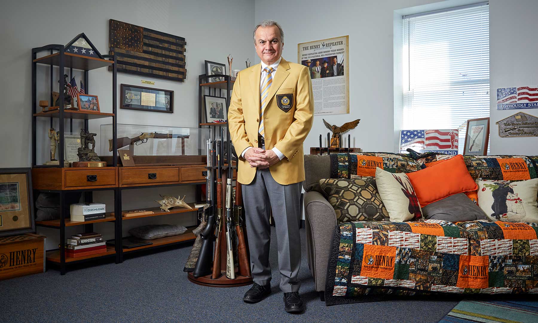 Henry Repeating Arms supporter stands in office filled with firearms, flags, and military memorabilia