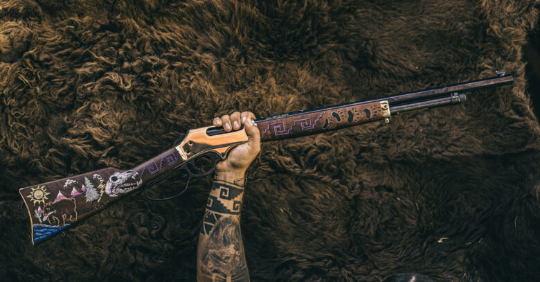 A hand holding up a rifle with a painted design on the wood.