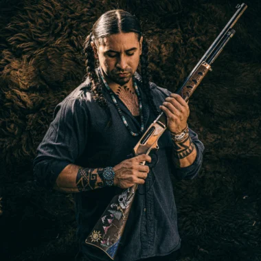 A man holding a tactical rifle in a wilderness setting