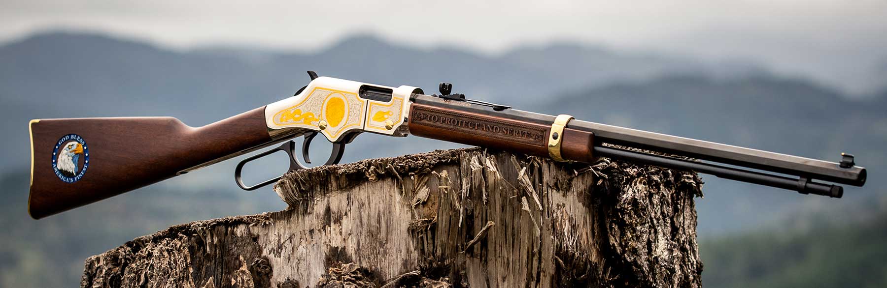 Henry lever-action rifle on weathered tree stump in mountains