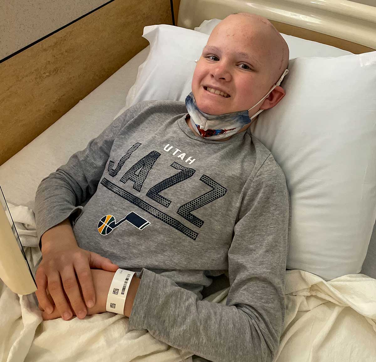 Smiling teenage boy in hospital bed holding limited-edition Henry rifle donated to support his brain cancer recovery