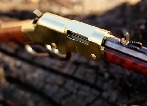 Henry Repeating Arms gold-plated 410 caliber lever-action shotgun on dark background