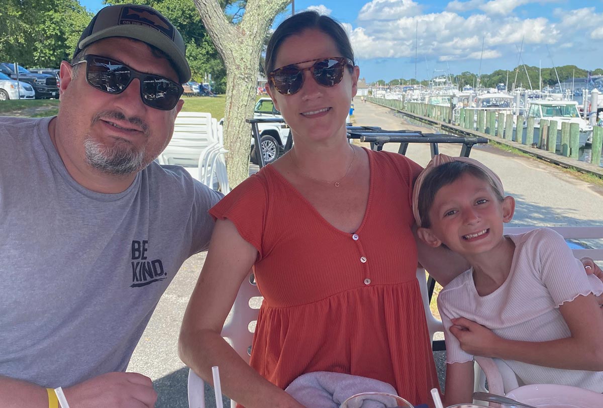 Family portrait of a father, mother, and young child outdoors at a marina