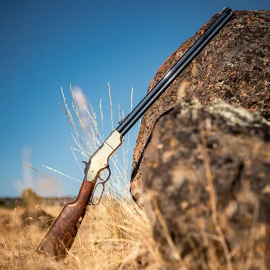 Henry Repeating Arms lever-action rifle with wooden stock and metal barrel against rocky terrain