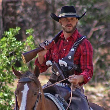 Cowboy riding horse and holding lever-action rifle in outdoor wilderness setting