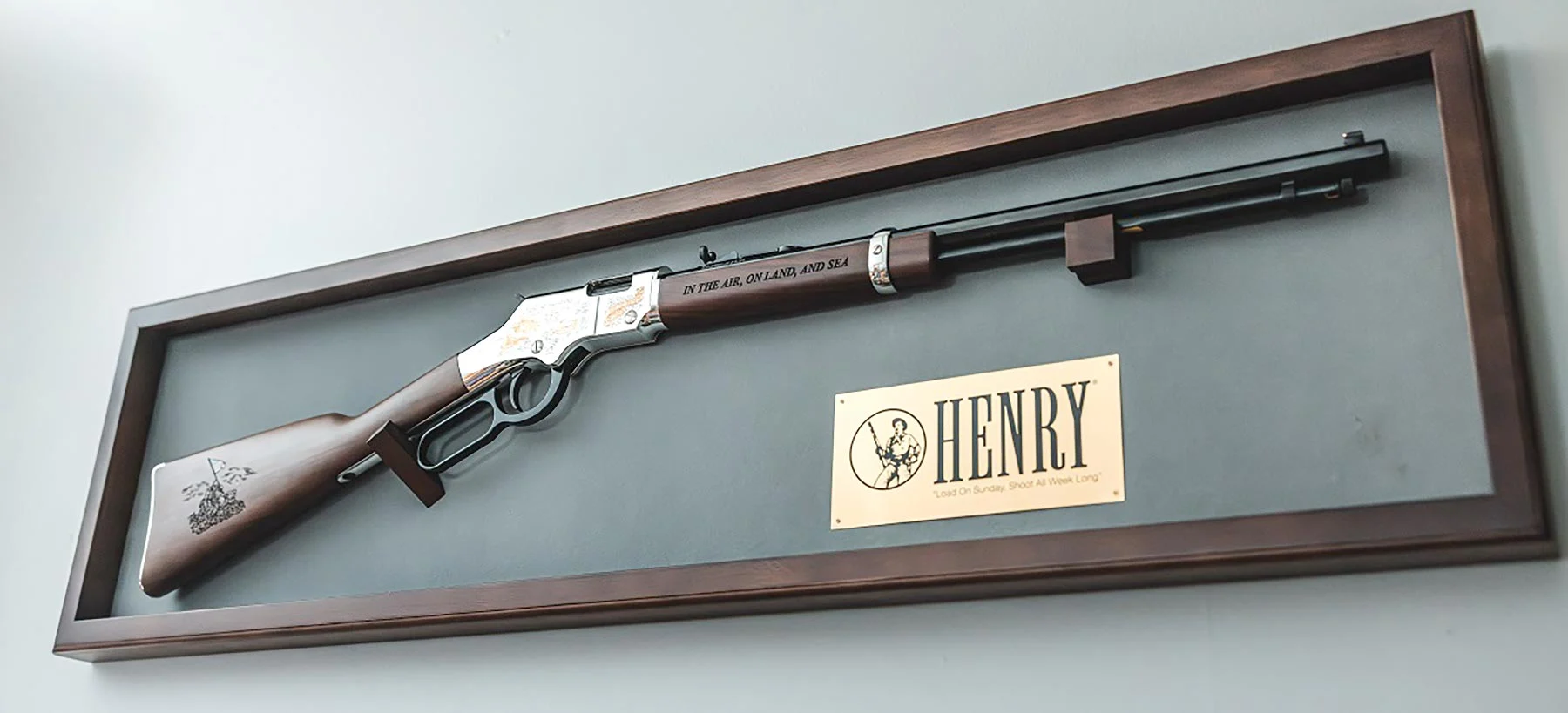 Three men in business suits standing with an award plaque displaying the Henry Repeating Arms logo and branding