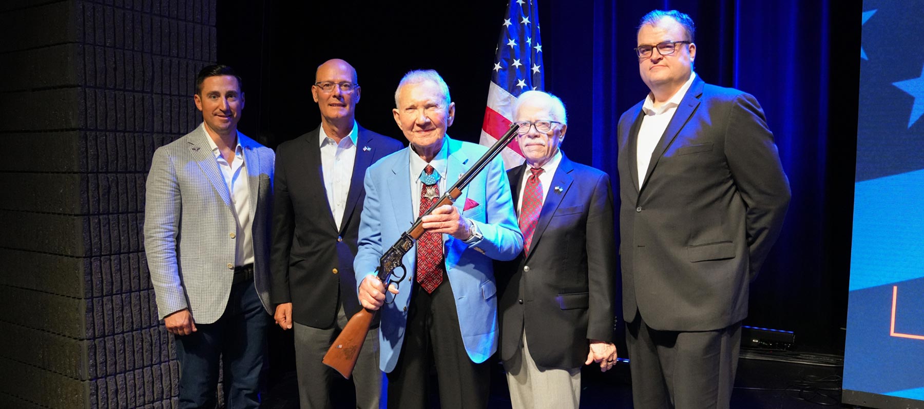 Three men in business suits standing with an award plaque displaying the Henry Repeating Arms logo and branding