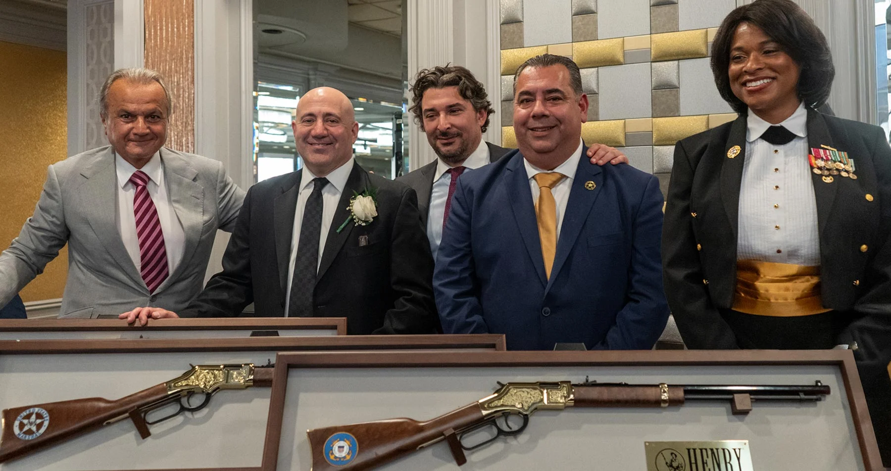Three men in business suits standing with an award plaque displaying the Henry Repeating Arms logo and branding