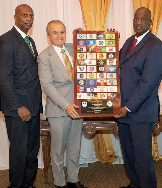 Three men in business suits standing with an award plaque displaying the Henry Repeating Arms logo and branding