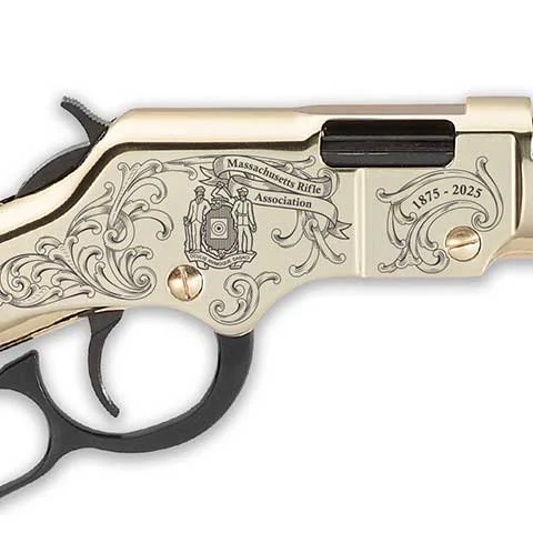 Decorative ivory-colored pistol with intricate floral engravings, Massachusetts Rifle Association emblem, and the dates 1875–2025.