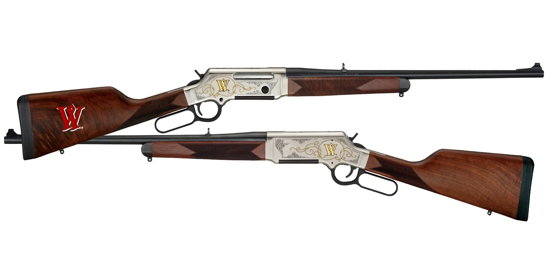 Two ornate lever-action rifles with silver engraved receivers and polished wooden stocks bearing a red 'W' emblem.