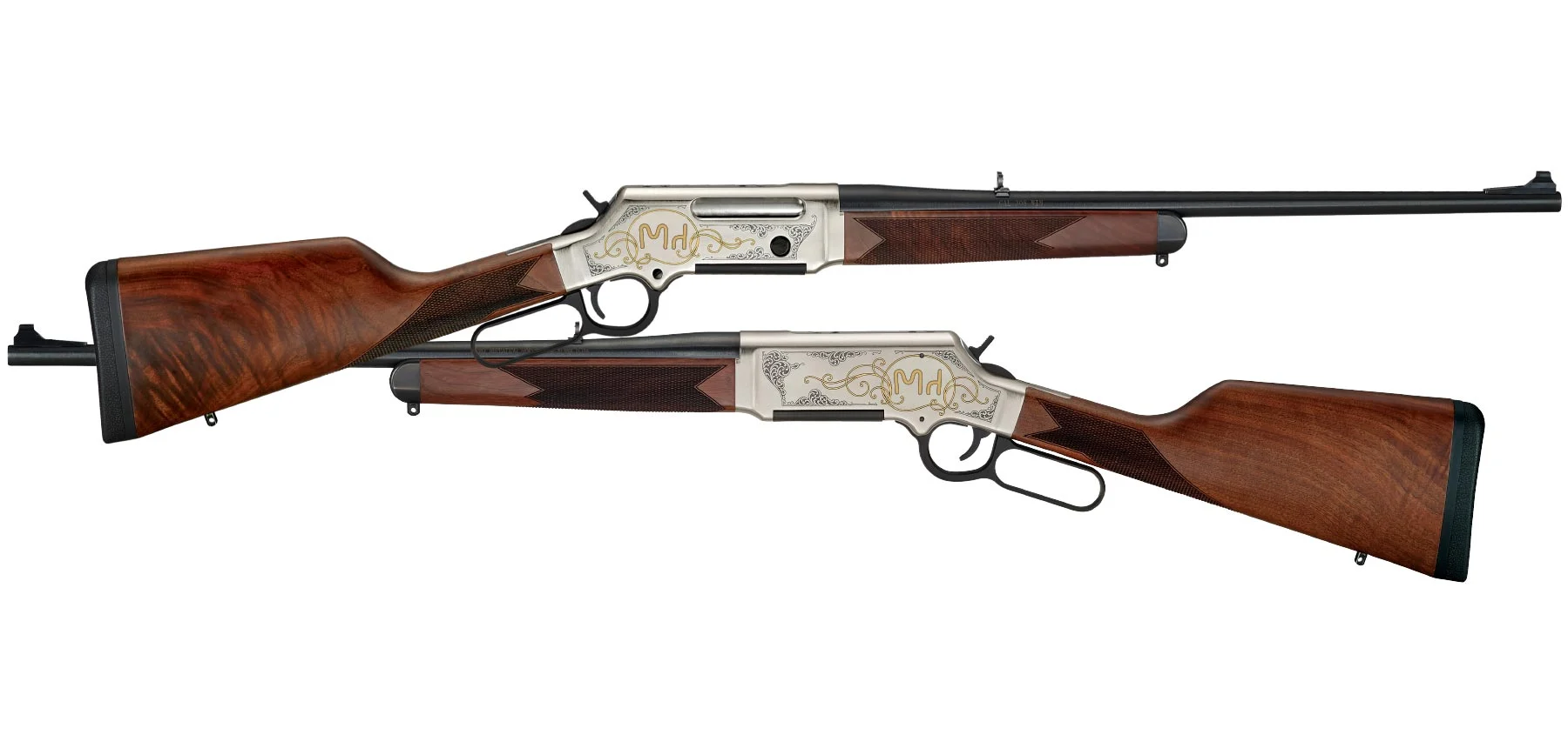 Pair of ornate over-under shotguns with carved walnut stocks and silver-engraved receivers laid side by side.