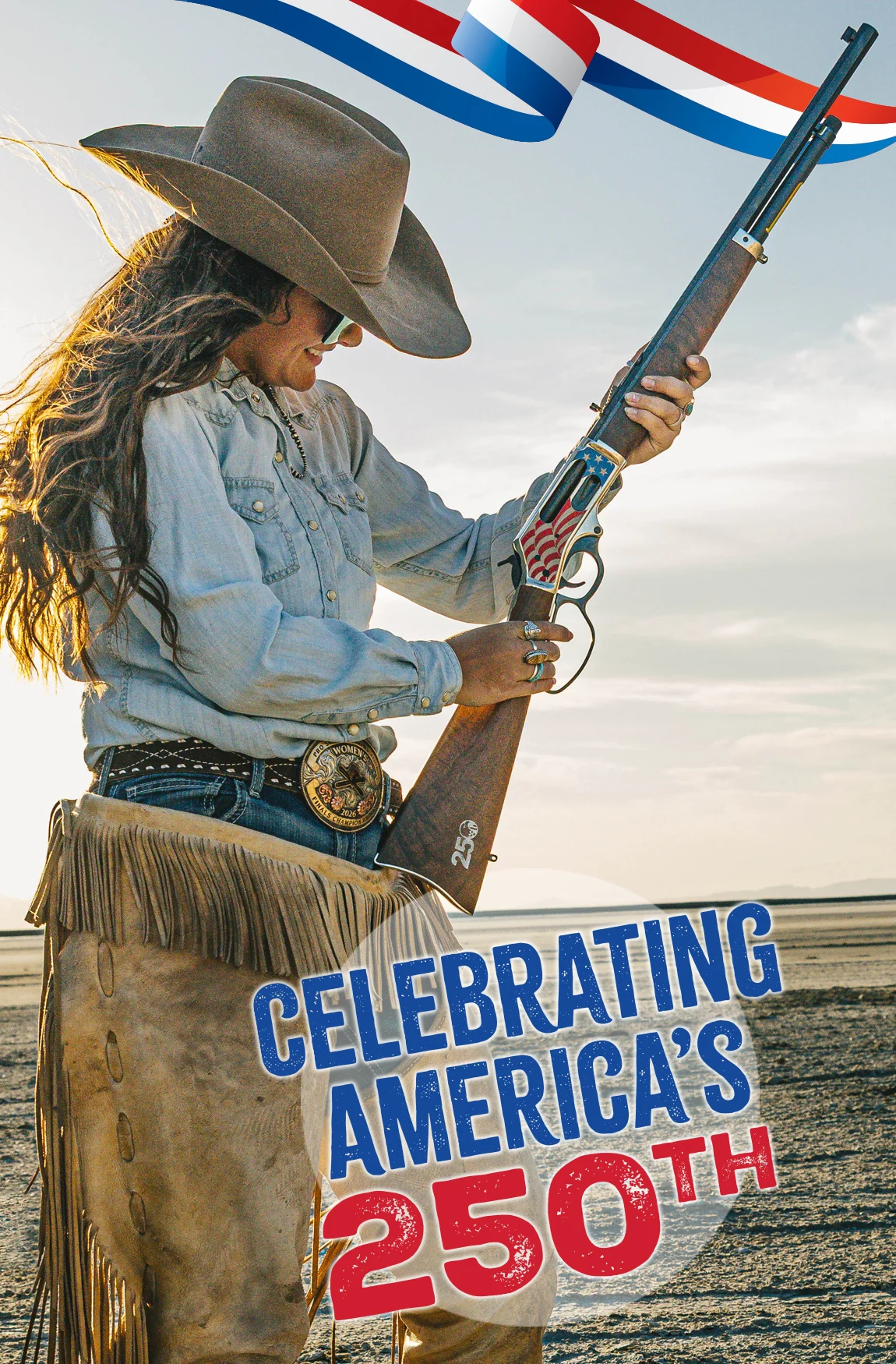 Woman in a wide-brimmed cowboy hat and denim shirt holding a lever-action rifle with patriotic decal, standing beside a banner that reads 'Celebrating America's 250th'