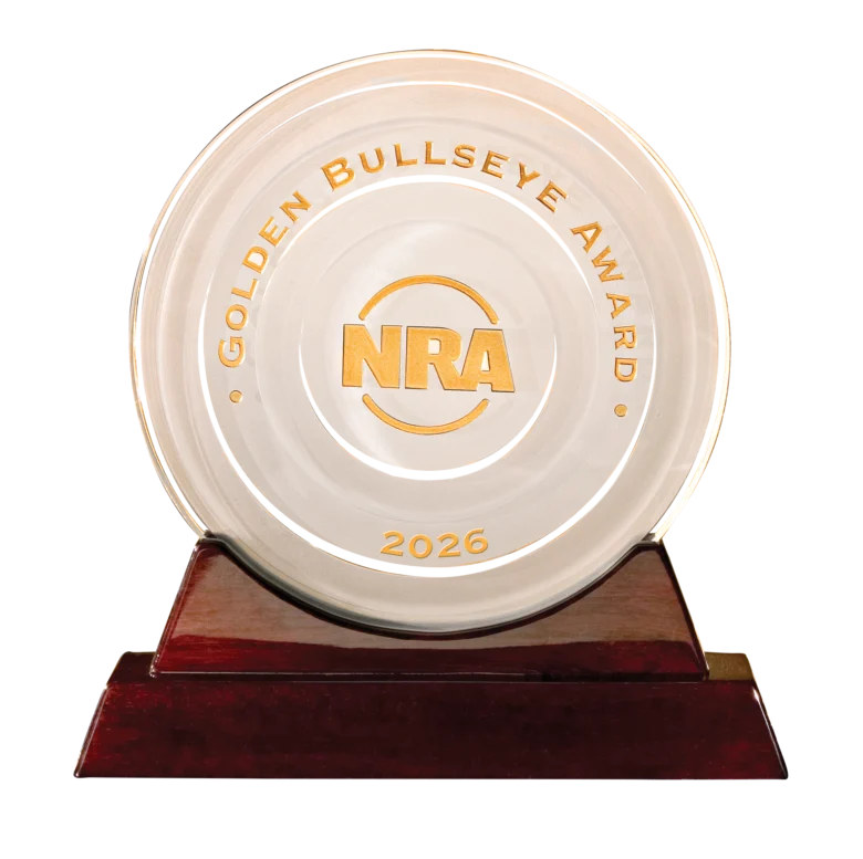 Close-up of a circular trophy with NRA logo and Gold Bullseye Award text, 2026 inscribed on the rim, mounted on a wooden base.
