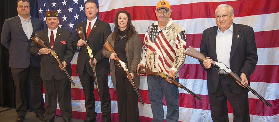 Five local heroes honored with Henry rifles at Great American Outdoor Show, standing in front of American flag