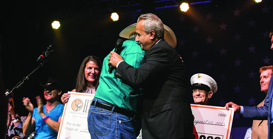 Two men hugging on stage at a music event honoring veterans